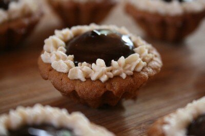 A peanut butter cookie tartelette filled with dark chocolate almond ganache and edged with Peanut butter infused whipped cream.